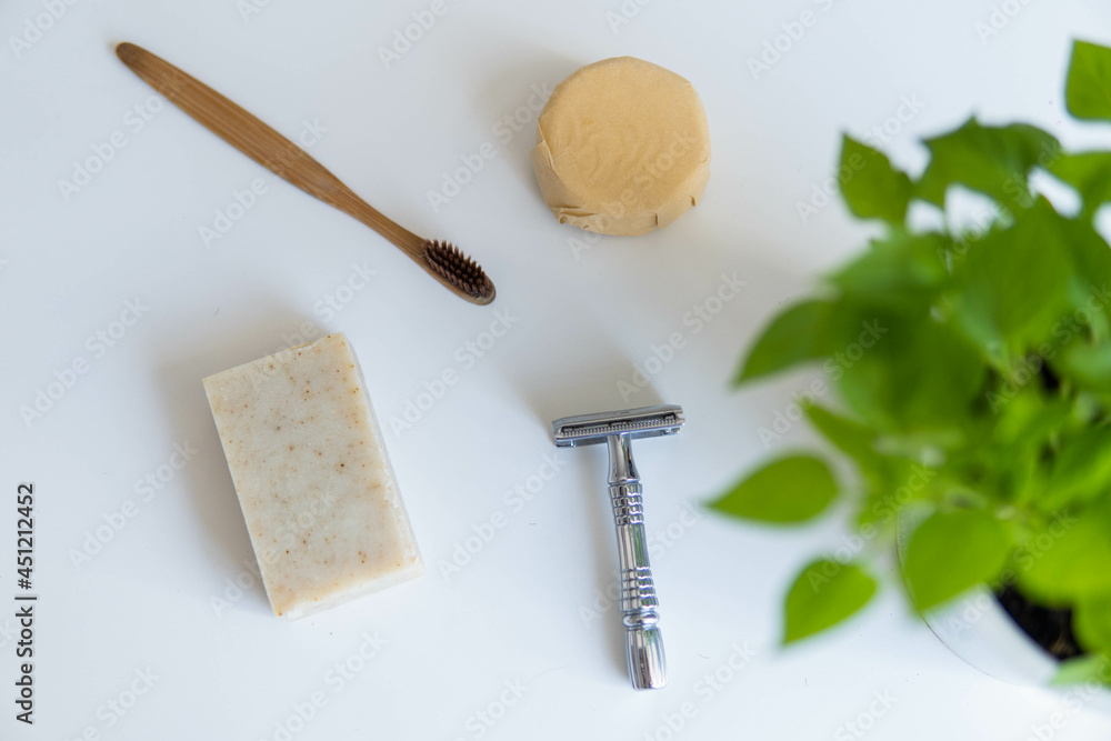 Zero waste product, close up caption. Bamboo toothbrush, solid shampoo, metal razor and solid hand soap. Sustainable bathroom products on a white background.