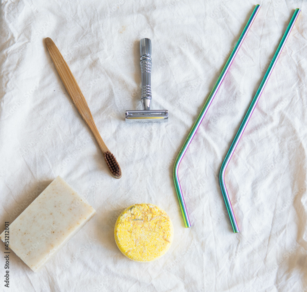 Zero waste product, close up caption. Bamboo toothbrush, solid shampoo, metal razor, metal straws and solid hand soap. Sustainable bathroom products on a white background.