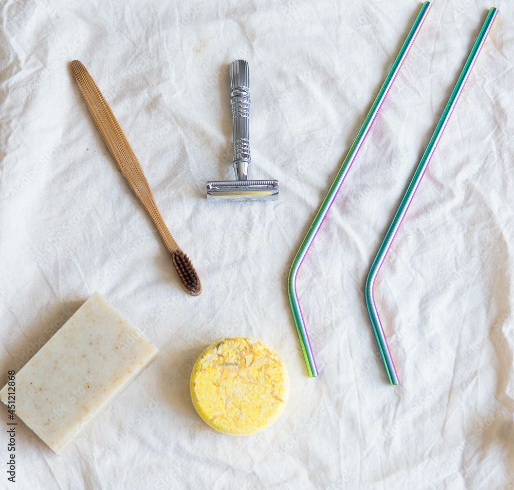 Zero waste product, close up caption. Bamboo toothbrush, solid shampoo, metal razor, metal straws and solid hand soap. Sustainable bathroom products on a white background.