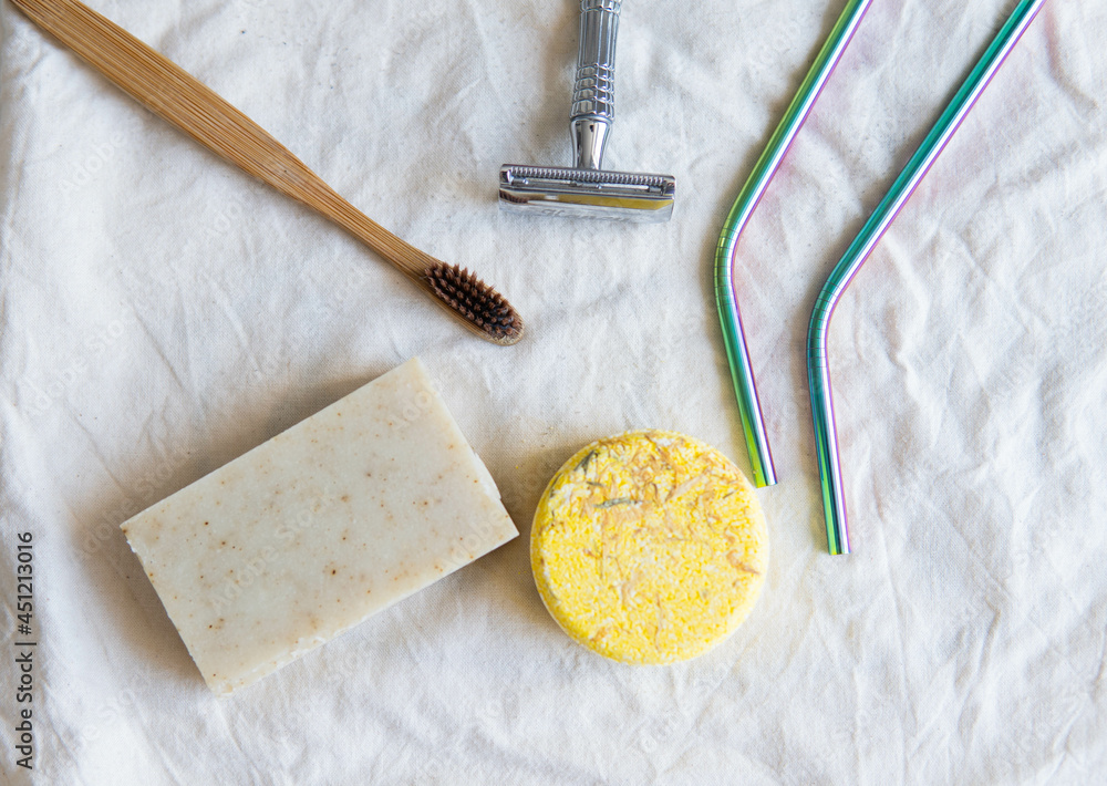 Zero waste product, close up caption. Bamboo toothbrush, solid shampoo, metal razor, metal straws and solid hand soap. Sustainable bathroom products on a white background.