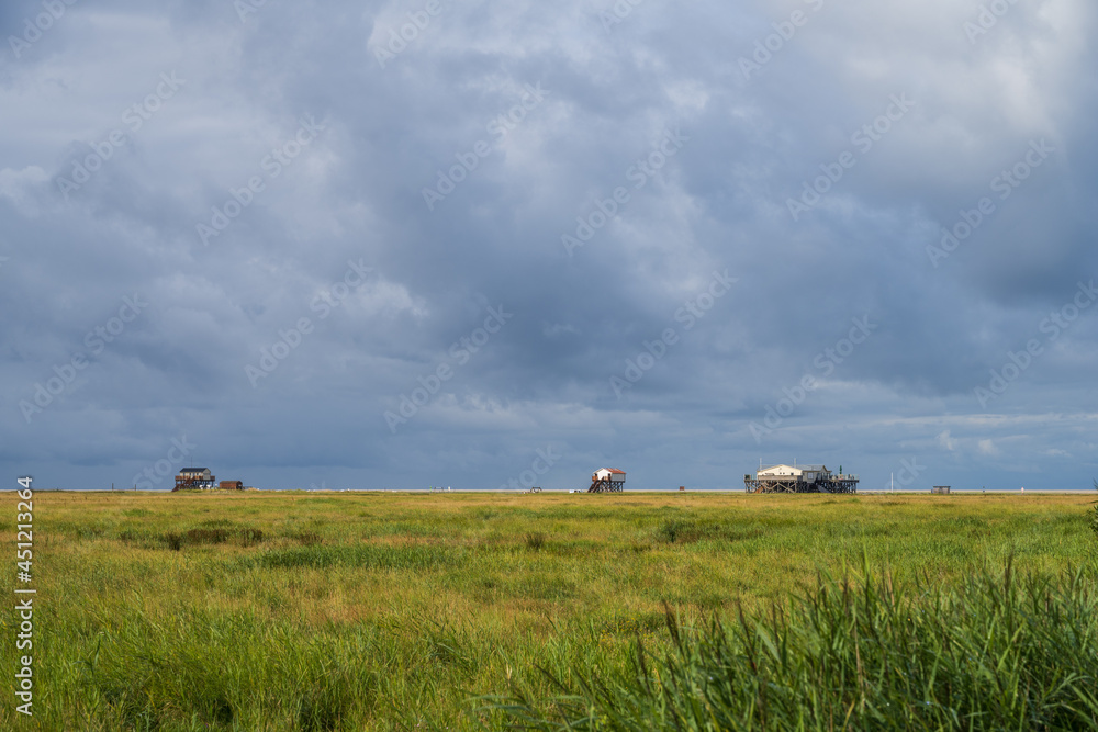 Pfahlbauten am Strand von Böhl an der Nordseeküste vor dramatischem Sommerhimmel