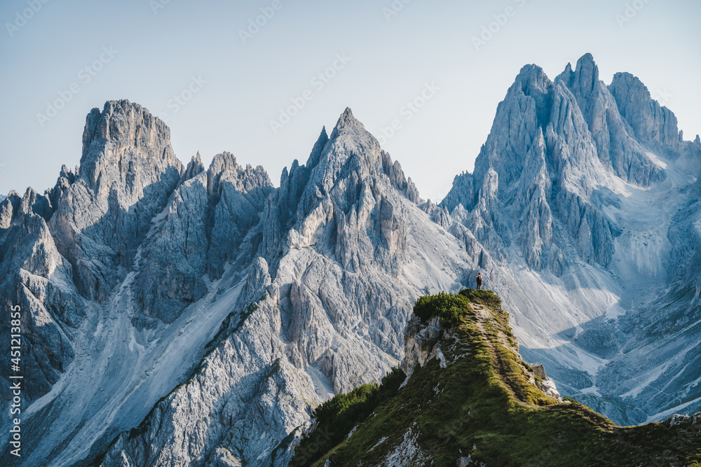 Man hiker standing and admiring stunning beauty of impressive jagged peaks of Cadini di misurina mountain group in Dolomites, Italy, part of Tre Cime di Levaredo national park