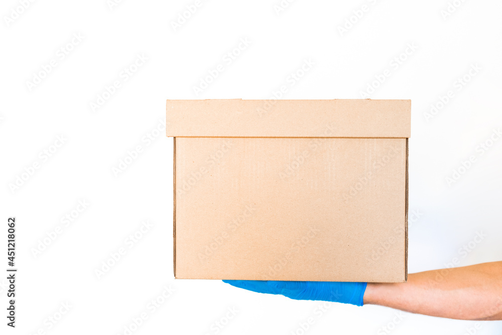 Delivery man holding cardboard boxes in blue rubber gloves with copy space. Fast and free Delivery transport . Online shopping and Delivery service concept Delivery man holding cardboard boxes in blue rubber gloves with copy space. Fast and free Delivery transport . Online shopping and Delivery service concept