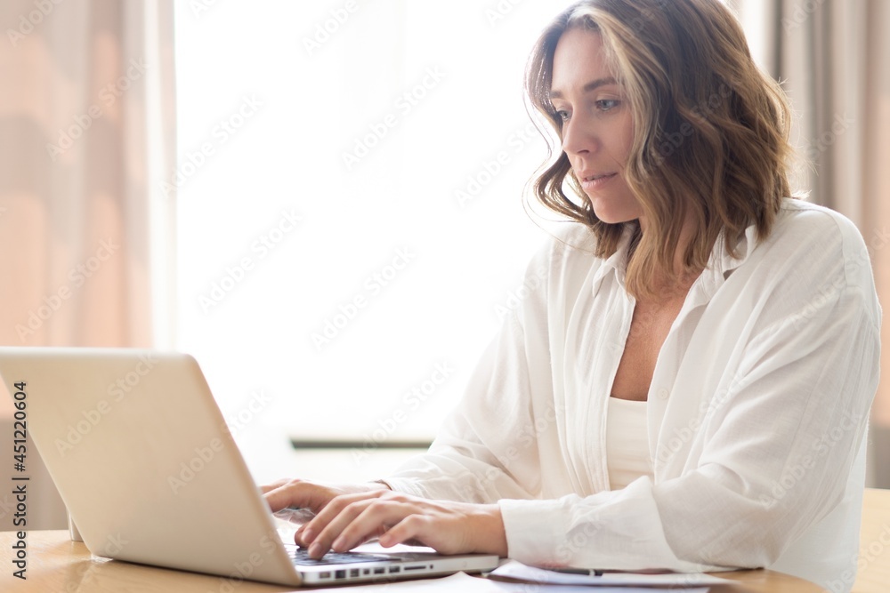 Beautiful young woman working from home on laptop.