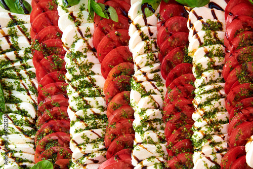 Caprese salad background. A lot of sliced tomatoes and mozzarella cheese covered with pesto sauce. Healthy lifestyle concept photo. Beautiful catering on event. Horizontal photo.