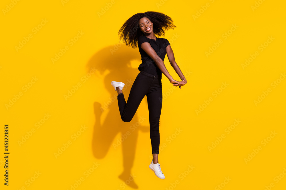 Full length body size photo curly girl jumping up smiling overjoyed happy isolated vivid yellow color background