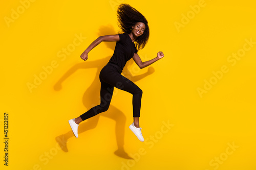 Full size profile side photo of happy nice young dark skin woman jump up runner sale isolated on yellow color background