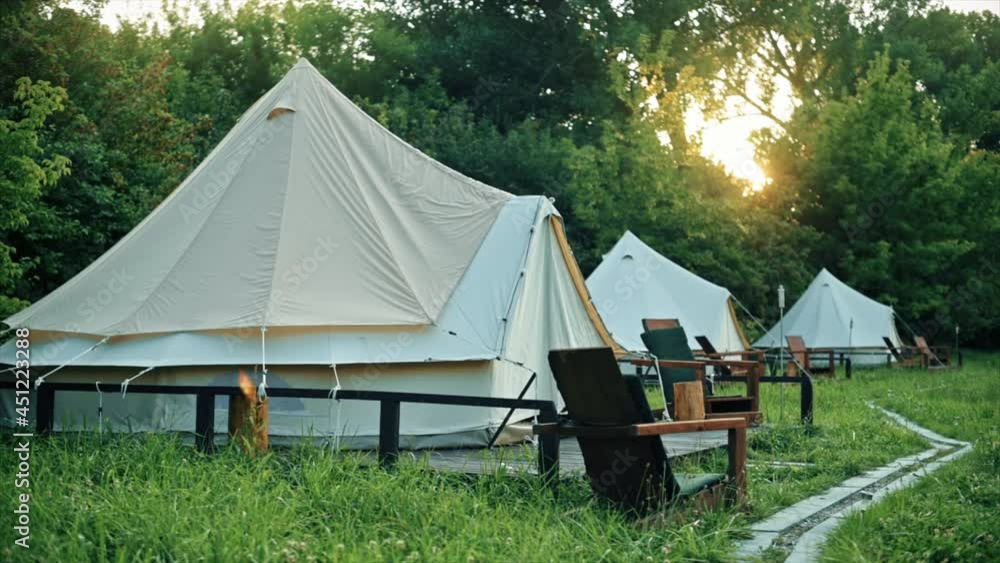 Glamping, few tents, chairs and pathway on the foreground, geenery around Glamping, few tents, chairs and pathway on the foreground, geenery around