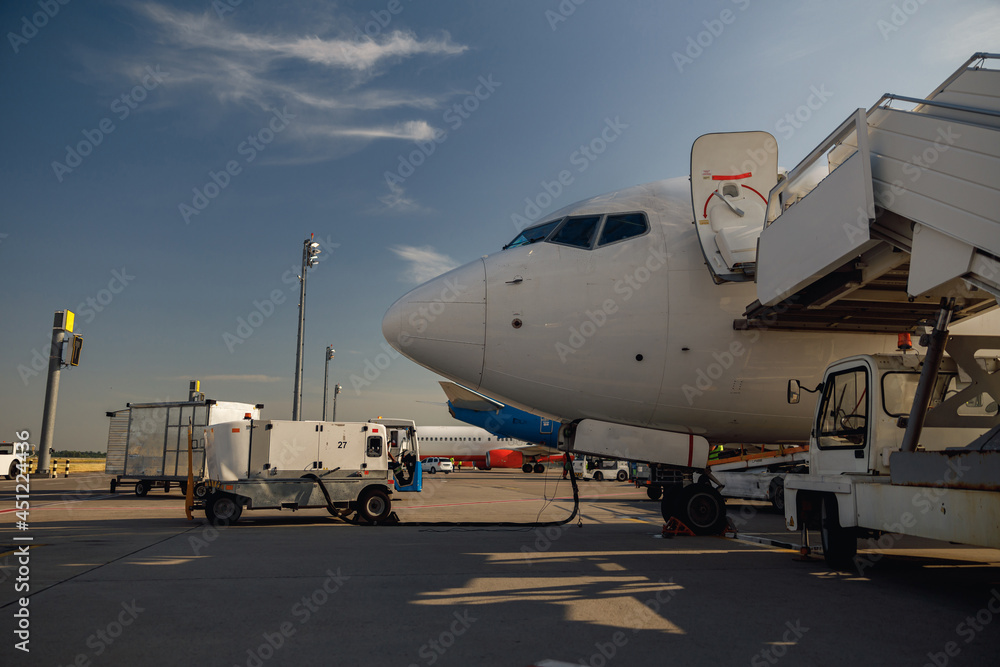 Fototapeta premium White airplane at airport refueling outdoors on a daytime. Aircraft details. Plane, shipping, transportation concept