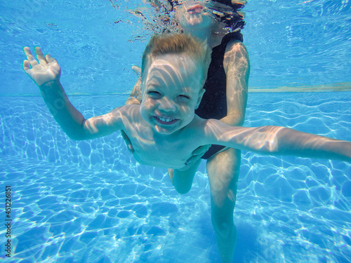 infant is underwater in the pool smiling