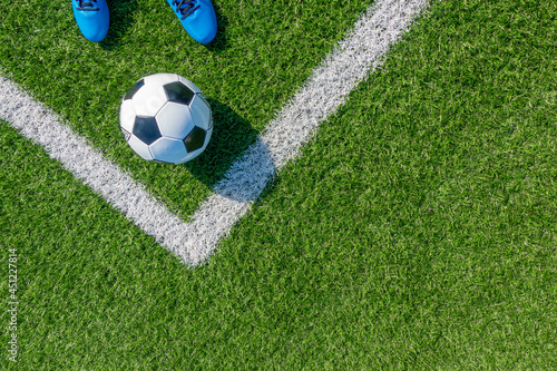 Soccer football background. Soccer ball and pair of football sports shoes on artificial turf soccer field with white line. Top view © vejaa