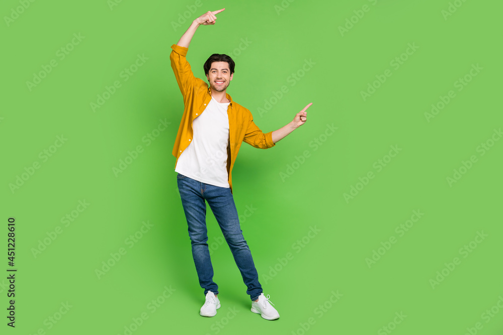 Full size photo of young handsome positive man point finger copyspace advertisement isolated on green color background Full size photo of young handsome positive man point finger copyspace advertisement isolated on green color background