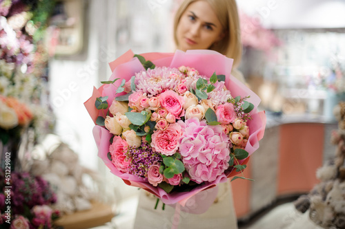 wonderful bouquet of pink chrysanthemum hydrangea and roses wrapped in paper in woman hands.