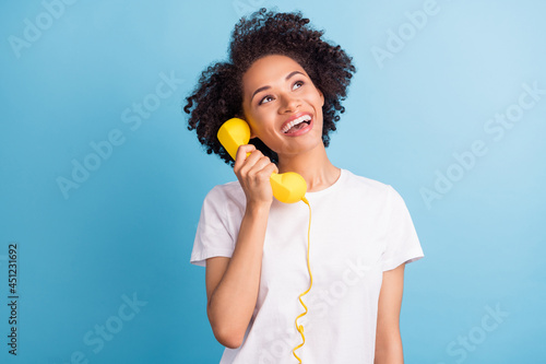 Photo of cheerful excited smiling african girl look copyspace dreaming talk on phone isolated on blue color background photo