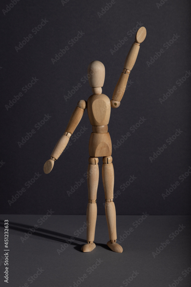 Wooden mannequin stands with raised hand on gray background. protest, attention concept. . copy space. Wooden mannequin stands with raised hand on gray background. protest, attention concept. . copy space.