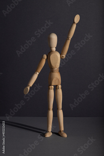 Wooden mannequin stands with raised hand on gray background. protest, attention concept. . copy space.