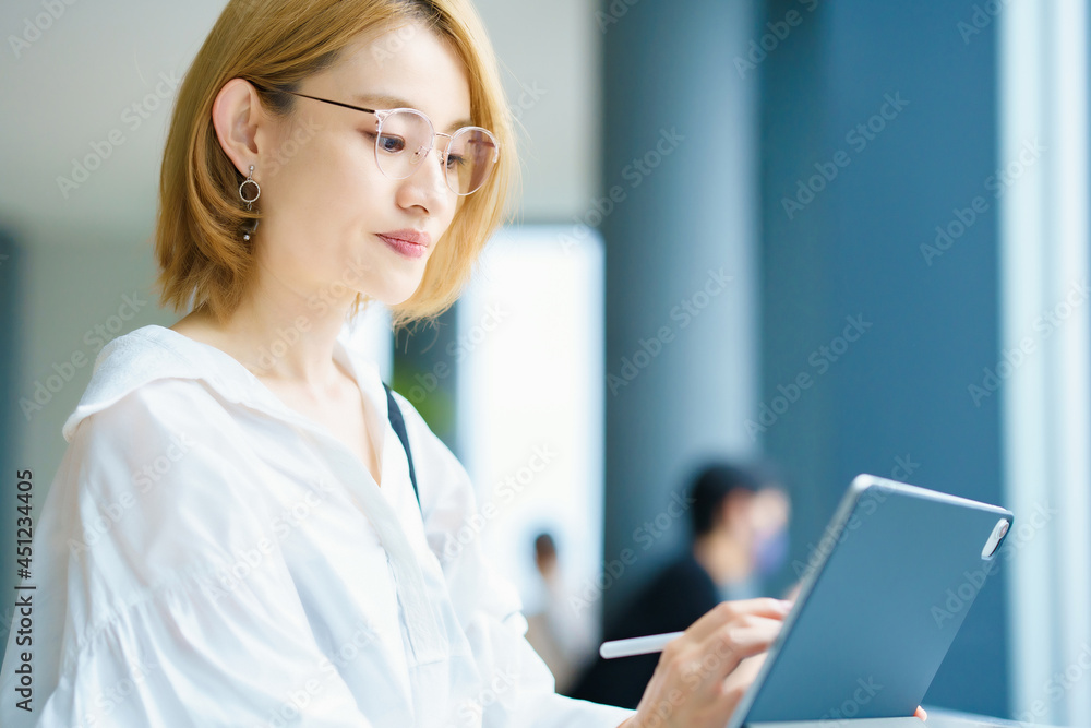 街なかでタブレットPCを操作する女性 街なかでタブレットPCを操作する女性