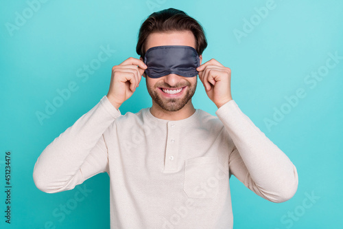 Photo of young man happy positive smile cover eyes bedtime nightwear isolated over turquoise color background