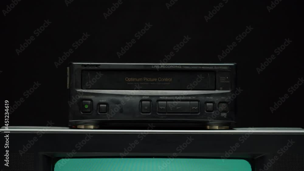 Taking video cassette from recorder. Old retro television with blue screen on black background. Old-fashioned TV, tv setting concept, ripples and interference, searching channel. Taking video cassette from recorder. Old retro television with blue screen on black background. Old-fashioned TV, tv setting concept, ripples and interference, searching channel.