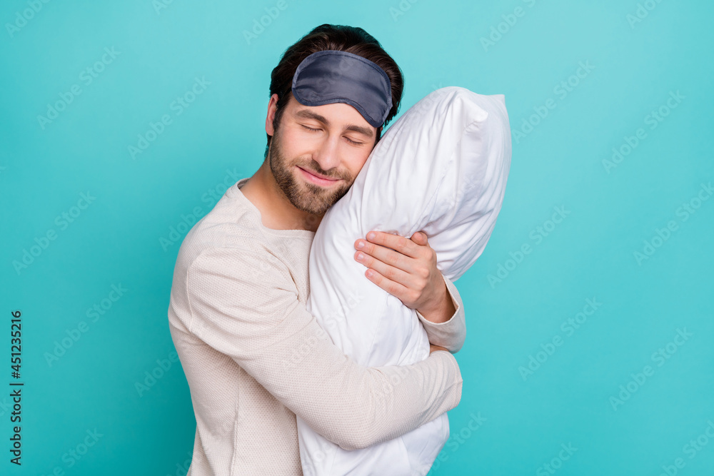 Profile side photo of young man happy positive smile cuddle pillow sleep night cozy isolated over teal color background Profile side photo of young man happy positive smile cuddle pillow sleep night cozy isolated over teal color background