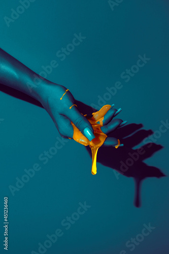 Crop model with orange paint flows on hand photo