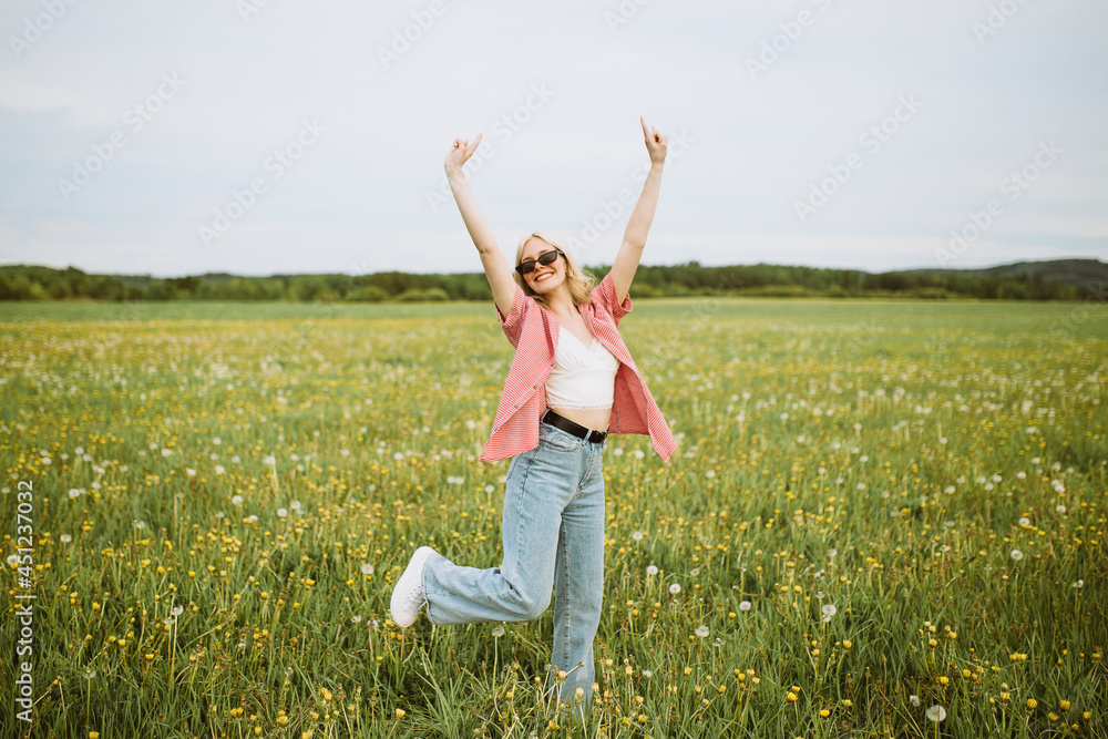 Cheerful woman showing horn gesture in summer field Cheerful woman showing horn gesture in summer field