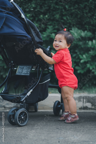 child standing by touch stroller for balance in development according to the age of the child with happy smile relax in evening time photo