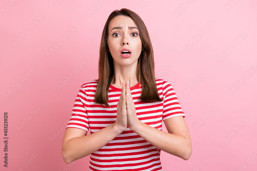 Photo of worried millennial brunette lady hold hands wear striped t-shirt isolated on pink color background Photo of worried millennial brunette lady hold hands wear striped t-shirt isolated on pink color background