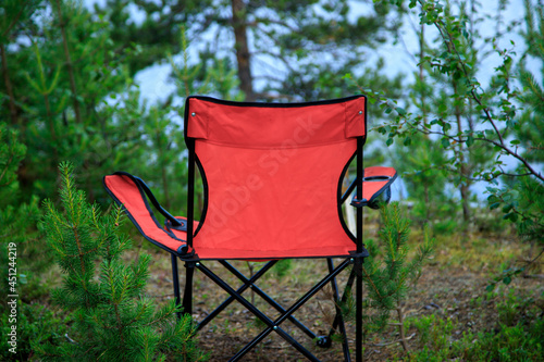 Lovely place. red tourist folder chair in the spruce forest