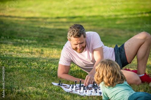 strategic and tactic. tutorship. dad and boy play logic game. father and son playing chess