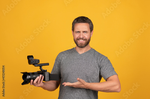 happy bearded man videographer presenting professional camcorder, product proposal photo