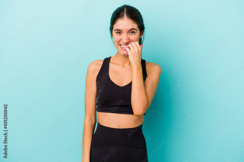 Young sporty caucasian woman isolated on blue background biting fingernails, nervous and very anxious. Young sporty caucasian woman isolated on blue background biting fingernails, nervous and very anxious.