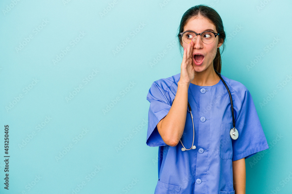 Young caucasian nurse isolated on blue background is saying a secret hot braking news and looking aside Young caucasian nurse isolated on blue background is saying a secret hot braking news and looking aside