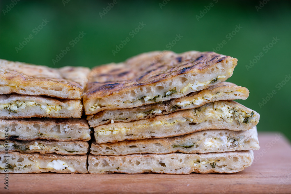 Pieces of baked dough tortilla with cottage cheese and herbs on a wooden table, close up