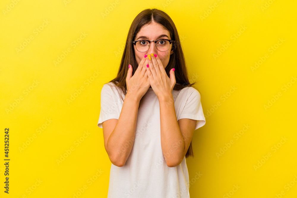 Young caucasian woman isolated on yellow background shocked, covering mouth with hands, anxious to discover something new. Young caucasian woman isolated on yellow background shocked, covering mouth with hands, anxious to discover something new.