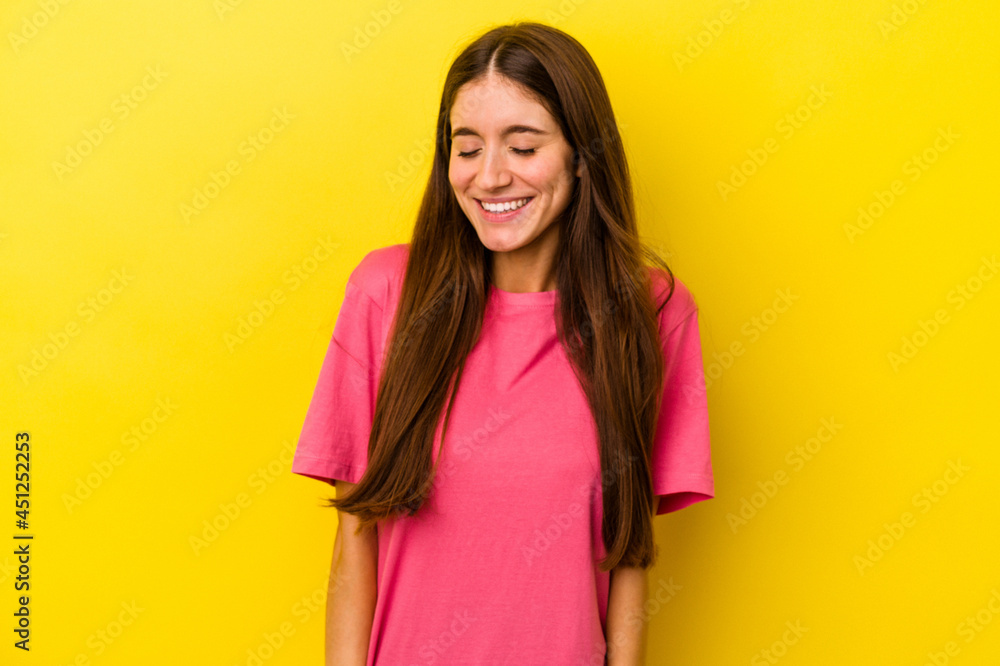 Young caucasian woman isolated on yellow background laughs and closes eyes, feels relaxed and happy. Young caucasian woman isolated on yellow background laughs and closes eyes, feels relaxed and happy.