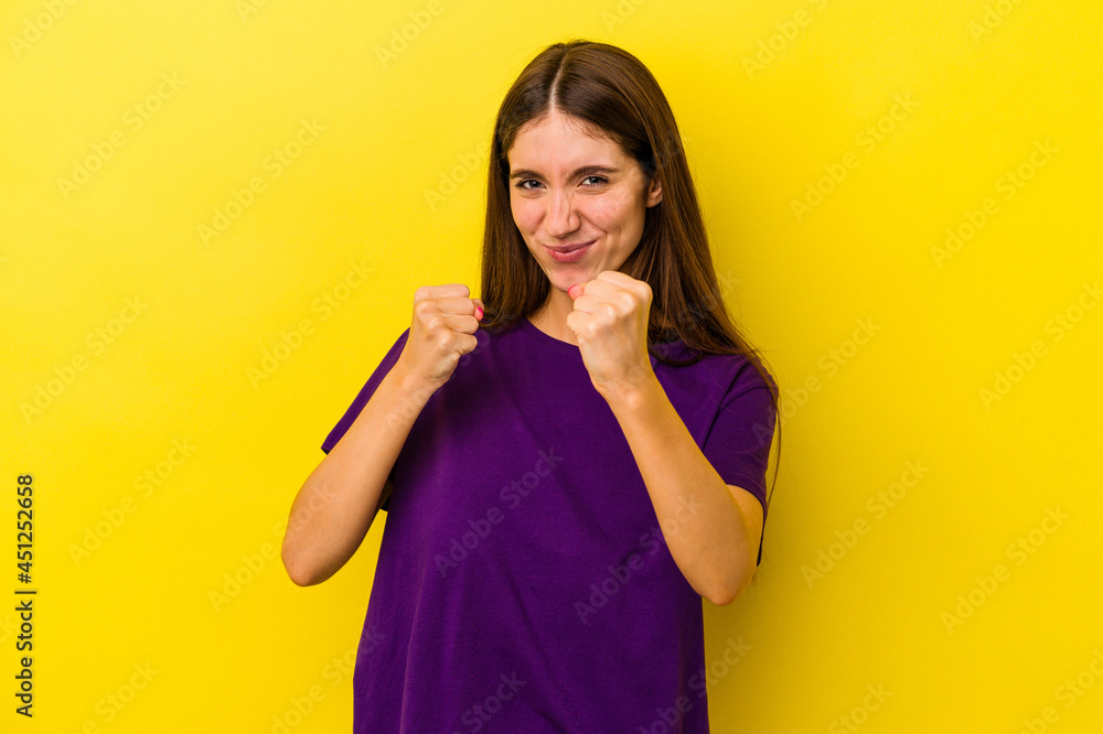 Young caucasian woman isolated on yellow background showing fist to camera, aggressive facial expression. Young caucasian woman isolated on yellow background showing fist to camera, aggressive facial expression.