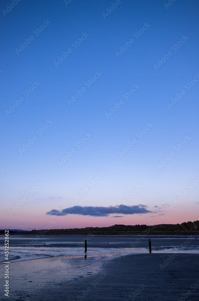 Singular low-hanging cloud above sand banks with gentle stream meandering down the beach; taken on cold winter morning at Tyrella beach in Northern Ireland.