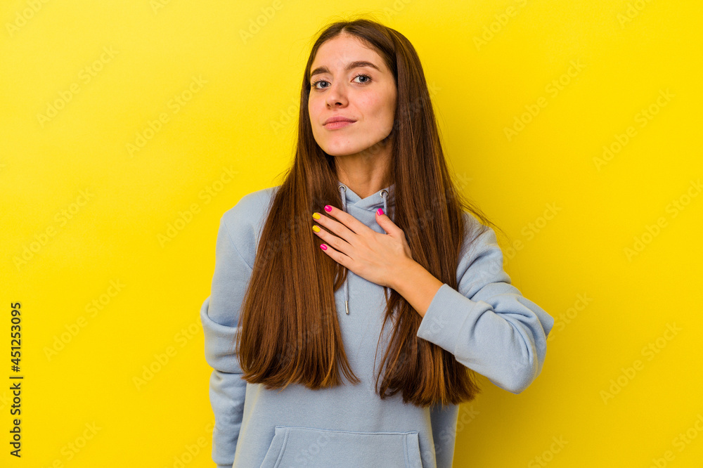 Young caucasian woman isolated on yellow background taking an oath, putting hand on chest. Young caucasian woman isolated on yellow background taking an oath, putting hand on chest.
