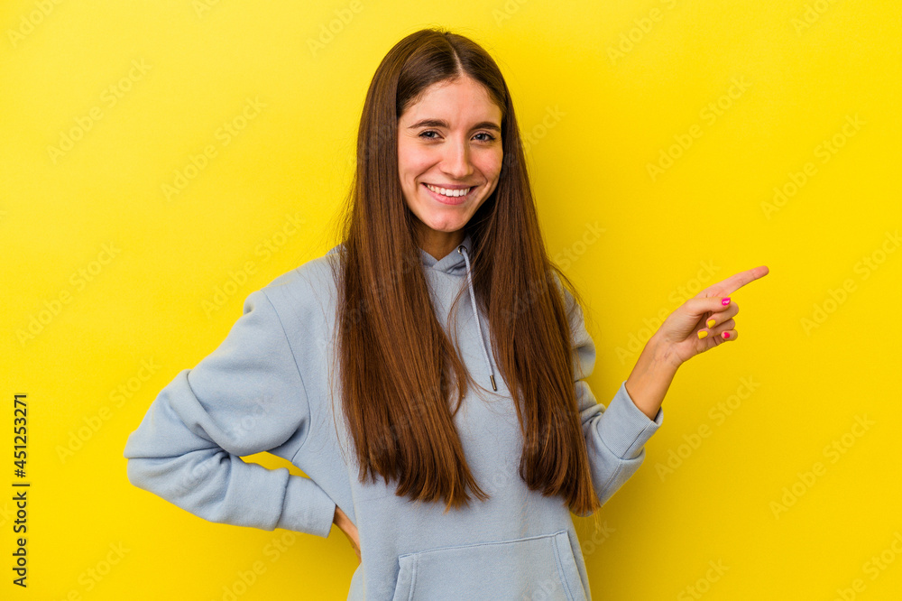 Young caucasian woman isolated on yellow background smiling cheerfully pointing with forefinger away. Young caucasian woman isolated on yellow background smiling cheerfully pointing with forefinger away.
