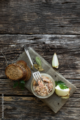 Stew in a glass jar, herbs and vegetables, bread on a wooden table. Preservation and storage of products.