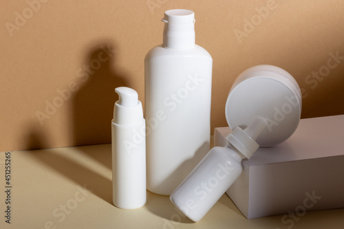 A set of female professional cosmetics for face and body care. Cosmetic tube with skin care product on beige background with hard shadows.