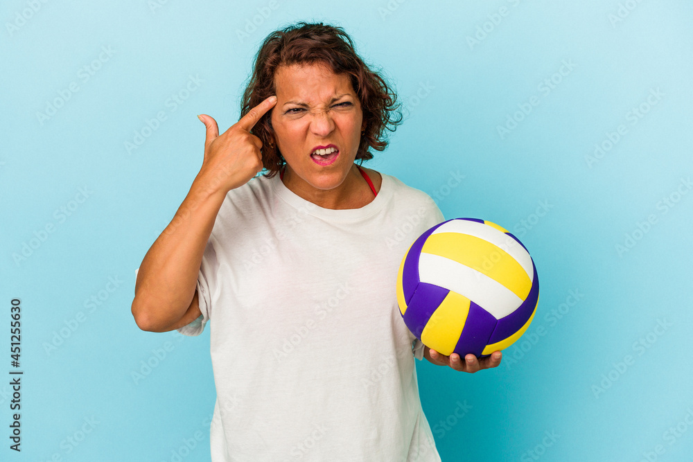 Middle age latin woman playing volleyball isolated on blue background showing a disappointment gesture with forefinger.