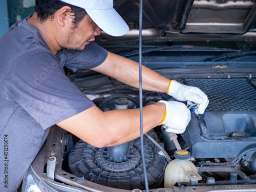 Mechanic holding a block wrench handle while fixing a car.