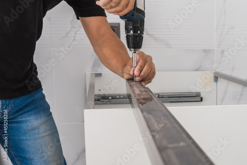 Man using a drill to place a nail between two pieces of furniture © Samuel Perales