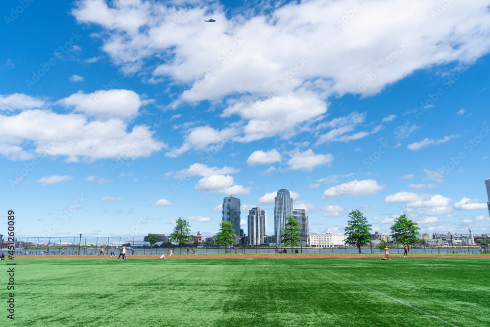 NEW YORK, USA – MAY 31: Clouds float over the John V. Lindsay East River Park Track in East Village on May 31, 2021 in New York City. High-rise residence buildings stand in Williamsburg Brooklyn ward.