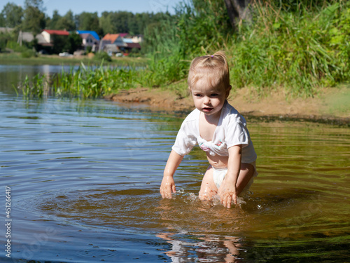 Fototapeta Naklejka Na Ścianę i Meble -  little girl splashing in the water near the shore