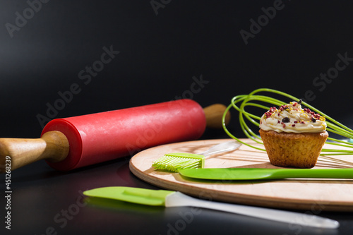 Home made cup-cake. Pastry tools with cup cake on black. Make best desserts yourself. photo