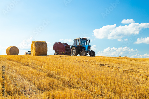 Bales of Hay in the Countryside and Tractor at Work in the background