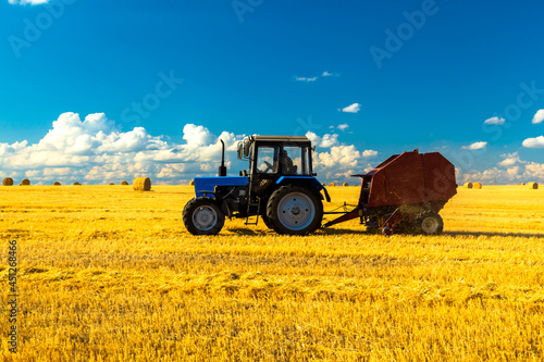 Tableau sur toile A tractor uses trailed bale machine to collect straw in the field and make round large bales